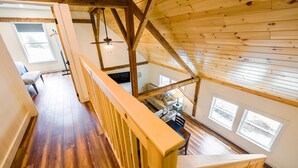 A spacious loft-style room with high ceilings, wooden beams, and large windows. - Historic Barn Suites (Greenville)