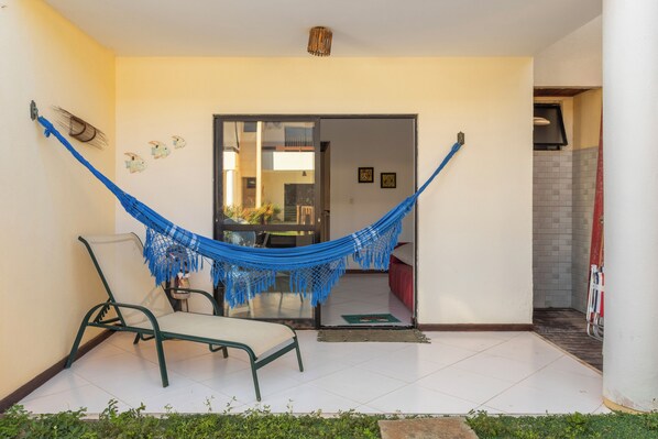 A room with a hammock, a chair, and a view of the interior.