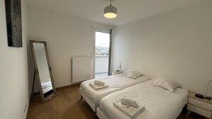 A hotel room with two beds, a bedside table, a nightstand, a mirror, and a window. - View Point Impérial Lake 4* - OG IMMO (Annecy)