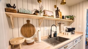 A kitchen with wooden shelves, a sink, and various kitchen items. - Southern Travel - Charming 3 BR (Moultrie)