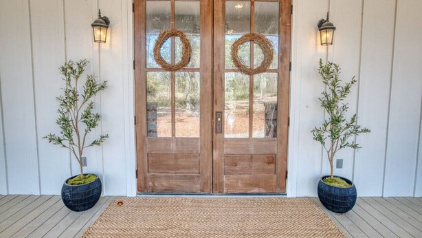 A wooden double door with glass panels, two wreaths, and two potted plants on either side. - Southern Farmhouse Retreat: 4 Bedroom, 4 Bath w/Master SPA like - Pet Friendly (Moultrie)