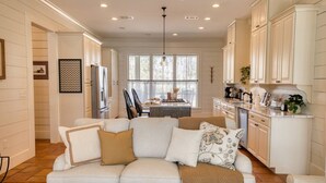 A modern kitchen with white cabinetry, a central island, and a dining area with a chandelier. - Southern Farmhouse Retreat: 4 Bedroom, 4 Bath w/Master SPA like - Pet Friendly (Moultrie)