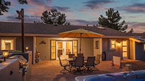 Un patio con jacuzzi, mobiliario exterior y una parrilla.