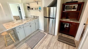 A kitchen with a stainless steel refrigerator, a microwave, and a marble countertop. - Wimble Shoals Chateau - Studio in Salvo above Surf Shop- (Salvo)