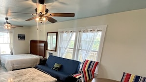 A compact room with a bed, a sofa, a dining table, and a ceiling fan. - Wimble Shoals Chateau - Studio in Salvo above Surf Shop- (Salvo)