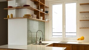 Una cocina moderna con armarios de madera, encimera de granito y ventana con luz natural.