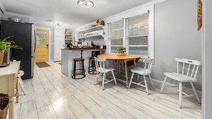 A modern kitchen with white cabinetry, a wooden island, and bar stools.
