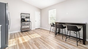 Eine Küche mit Kühlschrank, einer Kaffeestation und einer Essecke mit zwei Barhocker.