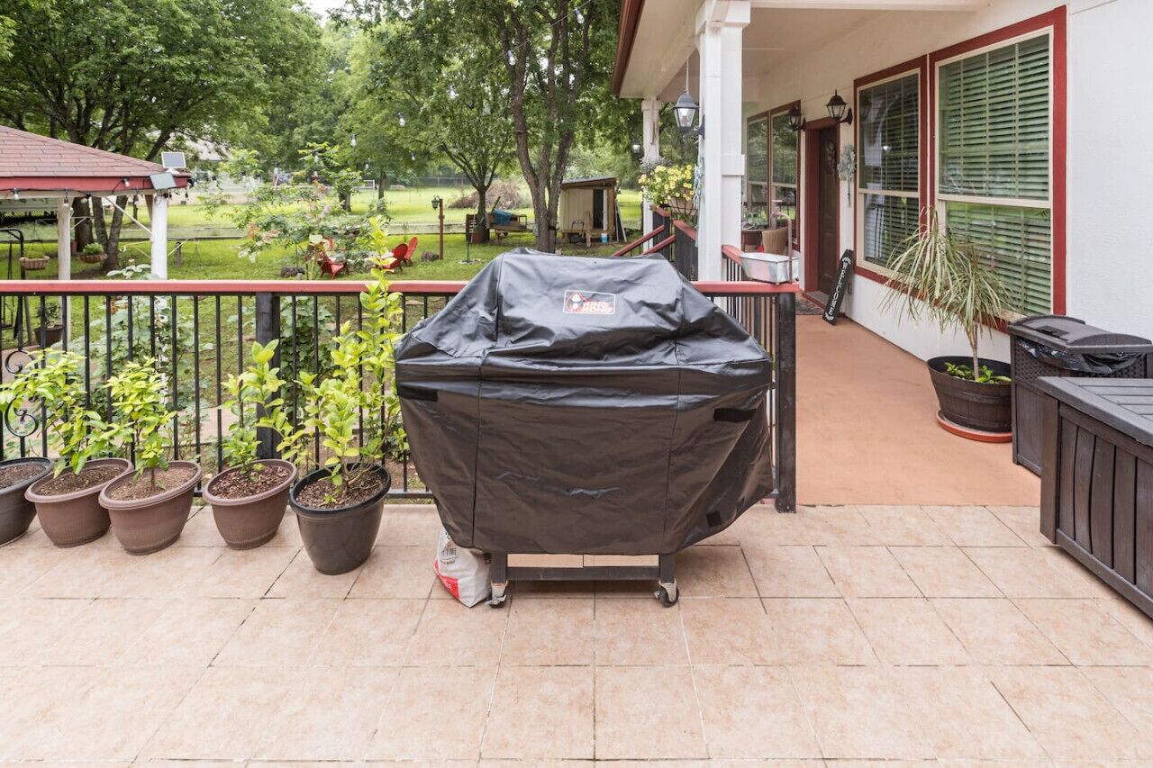 Une terrasse dotée d’un barbecue, de plantes en pot et d’un espace salon abrité.