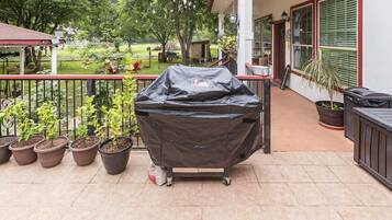 Une terrasse dotée d’un barbecue, de plantes en pot et d’un espace salon abrité.