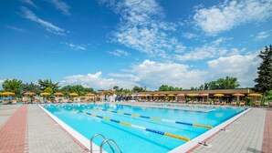 Ein Schwimmbecken mit Bahnen, Liegestühlen und Sonnenschirmen.