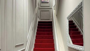 A staircase with red carpeted steps and white paneling on the walls. - Studio - Sleeps 3 - Near Ealing Broadway Station (London)