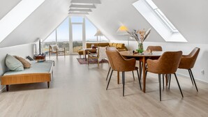 A spacious loft with a high ceiling, skylights, a dining area, and a view of the landscape.