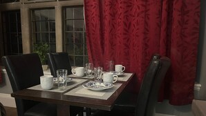 A dining table set with plates, cups, and glasses, surrounded by chairs. - Immaculate Studio in Bristol (Bristol)