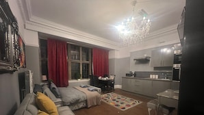 A modern living room with a grey sofa, red curtains, and a chandelier. - Immaculate Studio in Bristol (Bristol)