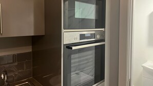 A kitchen with a double oven, stainless steel cabinets, and a tiled backsplash. - Immaculate Studio in Bristol (Bristol)