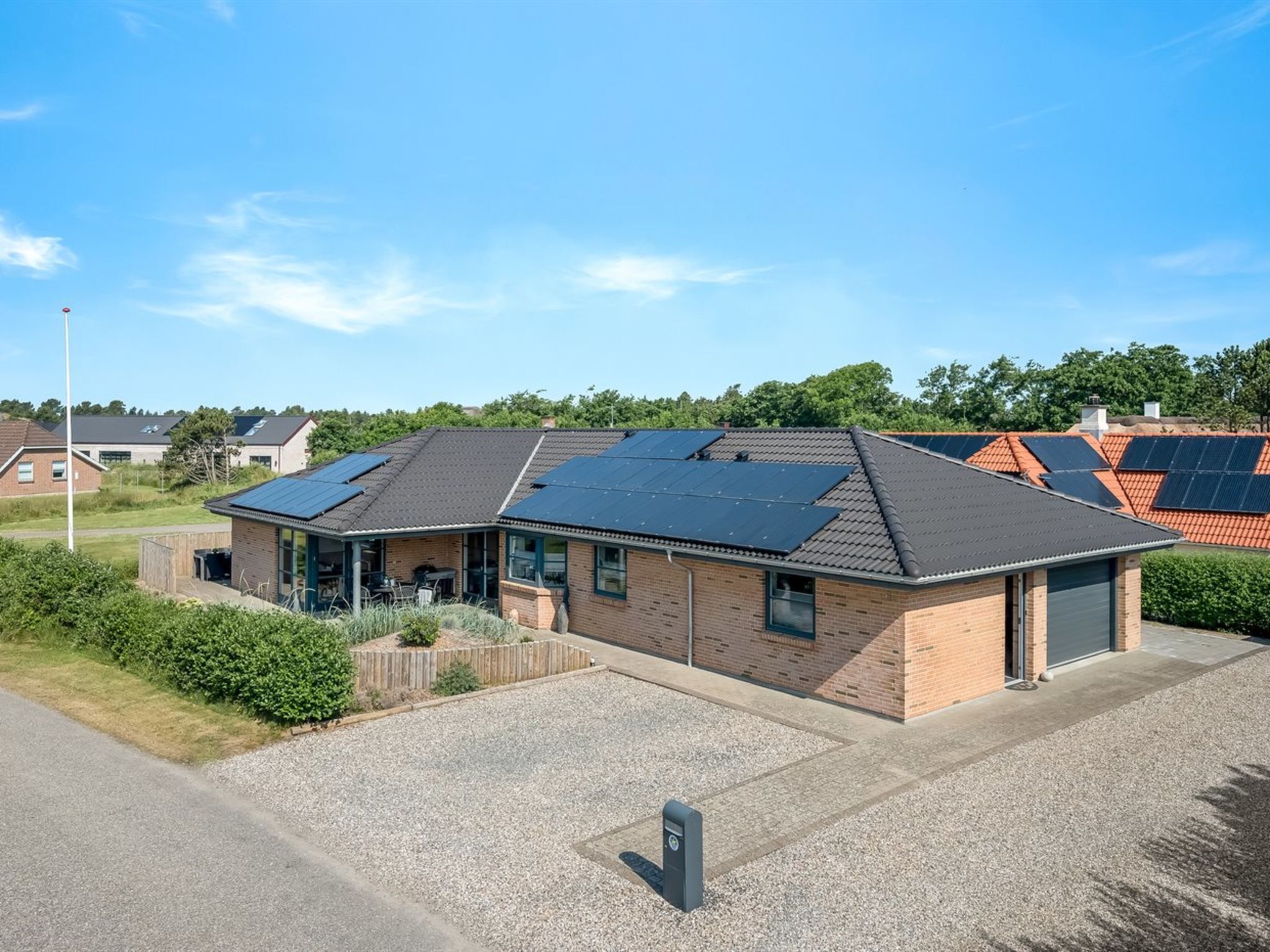 A building with a brick facade, a covered patio, and solar panels on the roof.