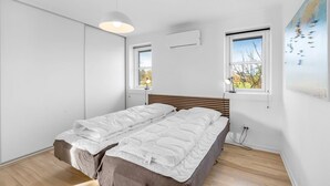 A bedroom with a bed, two windows, a pendant light, and a wall-mounted air conditioner. - "Elsi" - 1.3km from the sea by Interhome (Blåvand)