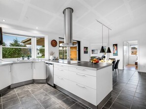 Een moderne keuken met een groot eiland, witte kasten en een roestvrijstalen afzuigkap.