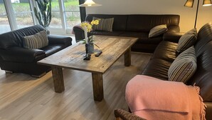 A living room with a wooden coffee table, two black leather sofas, a pink throw blanket, a potted plant, and a painting on the wall. - "Elsi" - 1.3km from the sea by Interhome (Blåvand)