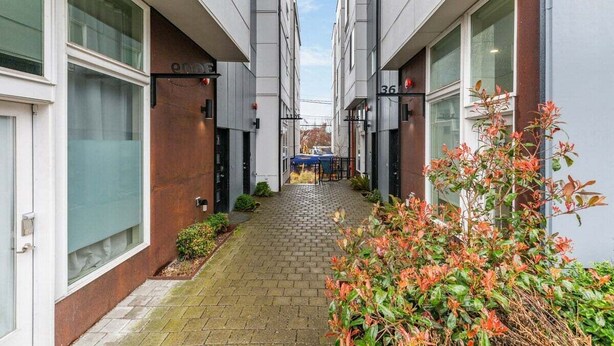 A narrow alleyway between two buildings with a small table and chairs in the center, suggesting a communal outdoor space. - Perch - Cozy Studio | Own Bath | Heart of Fremont (Seattle)