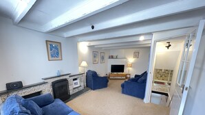 A living room with a fireplace, a TV, and two blue sofas.