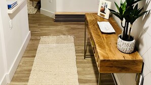 Un salon moderne avec une table basse en bois, une plante en pot et un miroir fixé au mur.