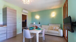 Un espace de vie compact comprenant un coin repas, une kitchenette et un coin salon avec un téléviseur.