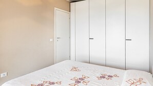 Une chambre à coucher avec un lit, une armoire et une porte.