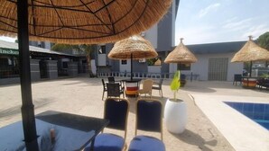 Zona de piscina amb gandules, una taula petita i sombrerets de palla.