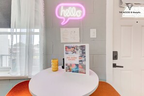 A reception area with a neon 'hello' sign, a welcome guide, and a door to the property. - Themed Lux Loft with King Bed, Free Parking & Wi-Fi (Memphis)
