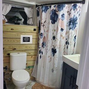A bathroom with a toilet, a wooden vanity, and a shower curtain with a floral pattern.