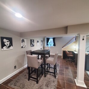 A dining area with a table and chairs, a rug, and wall art.