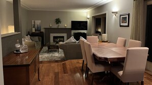 A modern living room with a fireplace, a dining table with chairs, a sofa, and a TV mounted on the wall. - Tranquil setting with beautiful views overlooking Skaha Lake  (Okanagan Falls)