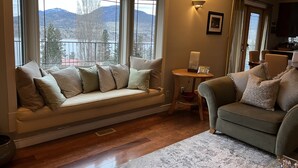 A cozy living room with a built-in bench by the windows, a small side table, and a grey sofa. - Tranquil setting with beautiful views overlooking Skaha Lake  (Okanagan Falls)