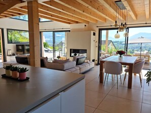 Relax in a serene space with a central seating area, dining table, and large windows offering views of the surrounding landscape.