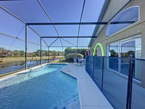 An outdoor swimming pool with a covered area, a view of a lake, and a building with large windows.