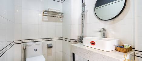 Un baño moderno con inodoro, lavamanos, espejo y ducha.
