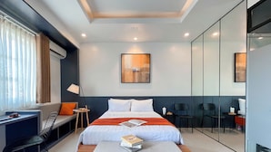 A modern hotel room with a large bed, a desk with a laptop, a chair, and a small table with a lamp. - Joi Hospitality - Hoang Anh (Ho Chi Minh City)