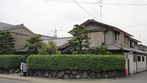 A traditional Japanese house with a stone wall and a well-maintained hedge. - Rakucho Ryokan (Kyoto)