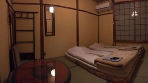 A traditional Japanese-style room with tatami flooring, a low table, and a futon bed. - Rakucho Ryokan (Kyoto)