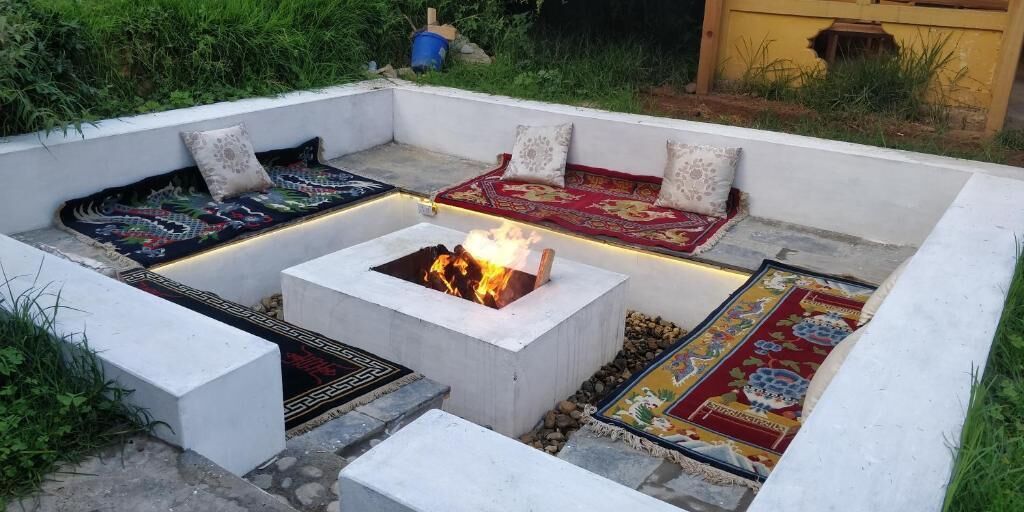 Un espace extérieur aménagé avec des sièges, un foyer et entouré de coussins et de tapis.