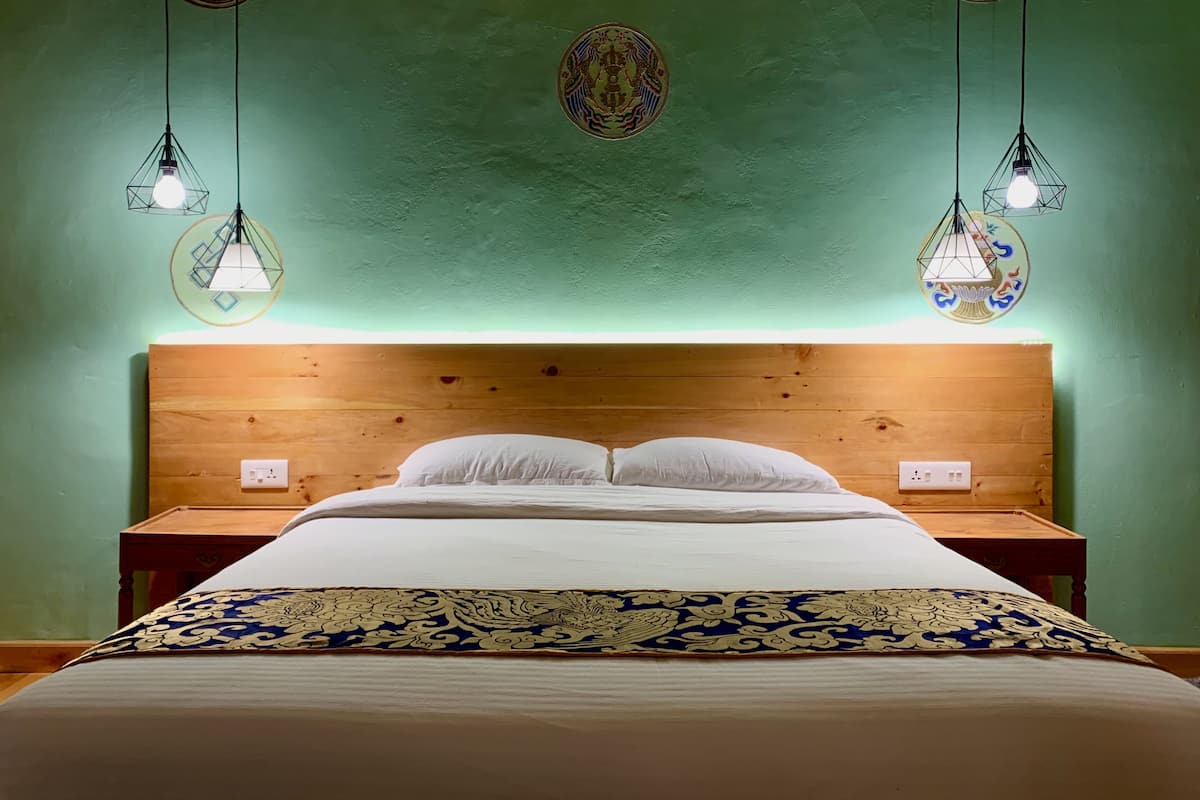 A neatly made bed with white linens and a decorative headboard.