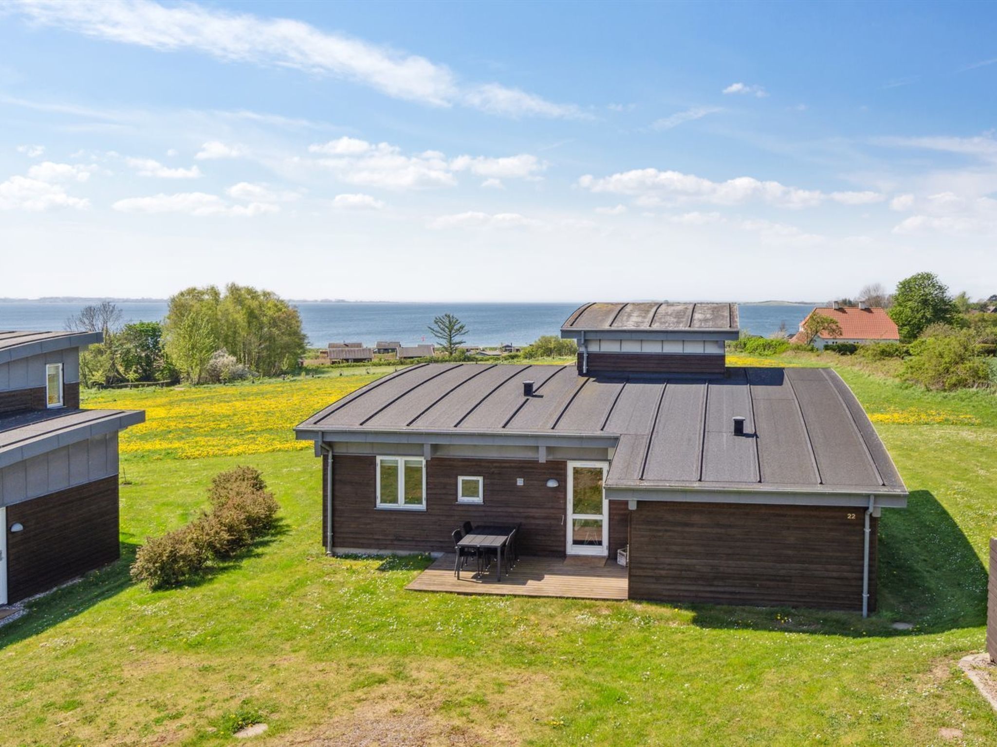 Une maison moderne avec un toit plat, une terrasse et une vue sur la mer.