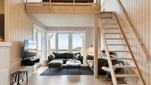 A spacious loft with a high ceiling, a wooden staircase, a large window offering a view of the landscape, and a cozy seating area with a flat-screen TV. - "Halvor" - 275m from the sea by Interhome (Faaborg)