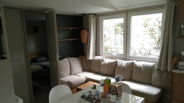 A compact living space with a sofa, a dining table, and a window with curtains.