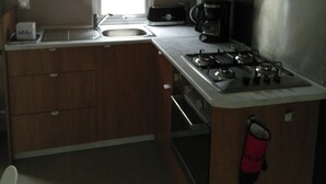 A compact kitchen with wooden cabinets, a microwave, a coffee maker, and a gas stove.