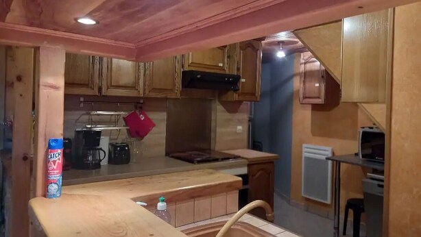 A kitchen with wooden cabinets, a stove, and a sink. - Maison de Village (Viella)