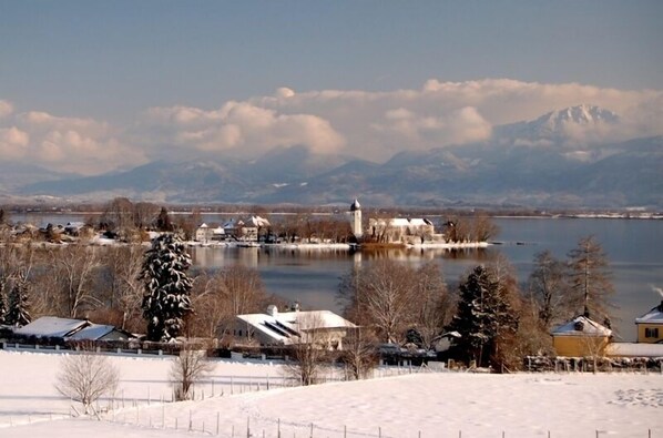 Un paisaje invernal con un lago, casas cubiertas de nieve e iglesia en una isla.