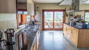 A modern kitchen with a large island, stainless steel appliances, and a view of the outdoors.